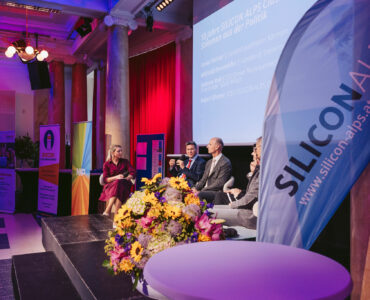 Seitansicht bei der Talkrunde bei 10 Jahre SILICON ALPS, davor eine Flagge